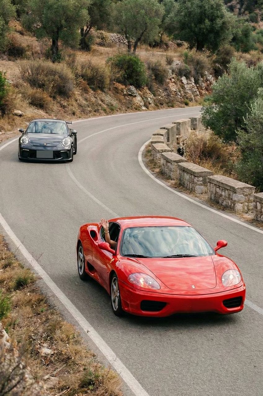 Ferrari y Porsche clásicos en una carretera de curvas de los Pirineos durante la Transpir